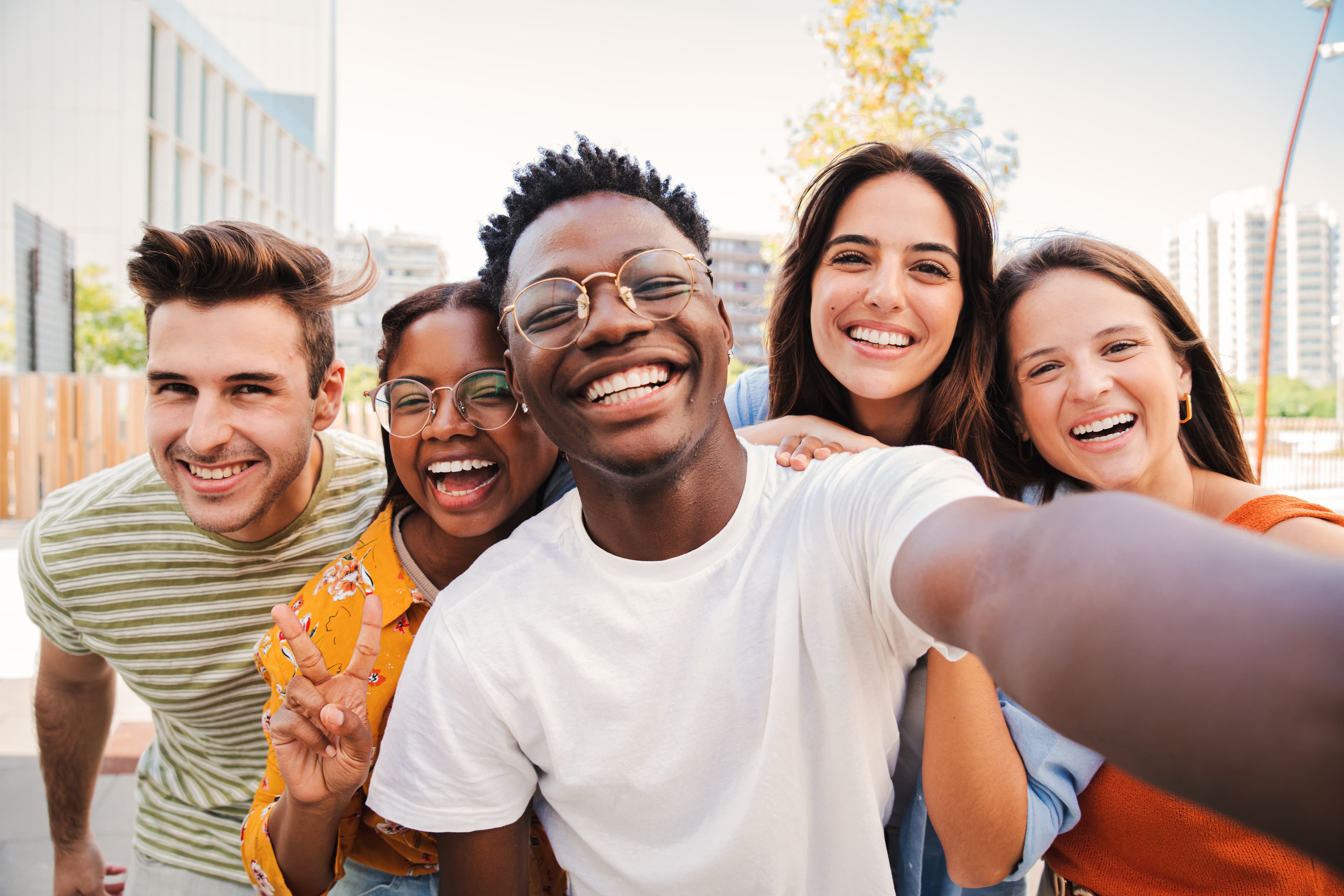 Diverse group of friends smiling and laughing together in an outdoor city selfie
